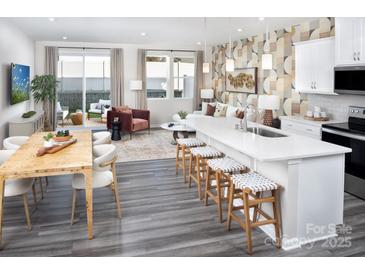 Open concept kitchen and dining area features an island with bar seating and stainless steel appliances at 3095 Big Bend Dr, Kannapolis, NC 28025
