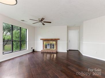 Bright living room with fireplace, ceiling fan, and large windows overlooking a treed front yard at 8202 Cedar Glen Dr, Charlotte, NC 28212