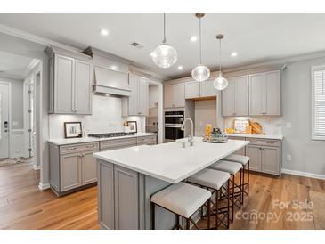 A spacious kitchen featuring an island with seating, stainless steel appliances, and pendant lighting at 9842 Quercus Ln, Huntersville, NC 28078