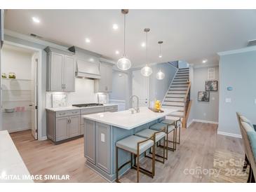 Modern kitchen featuring an island with seating, pendant lighting, and stainless steel appliances at 9842 Quercus Ln, Huntersville, NC 28078