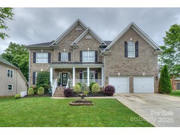Beautiful two-story brick home with a well-manicured lawn, front porch, attached two-car garage, and decorative fountain at 10304 Squires Way # 18, Cornelius, NC 28031