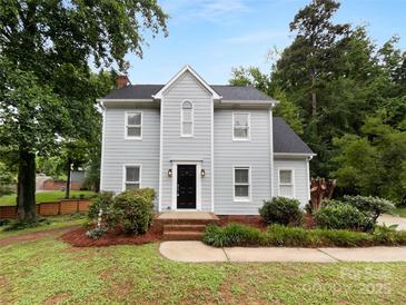 Charming two-story home featuring a well-maintained front yard with mature trees and a classic black front door at 124 Creek Hollow Trl, Belmont, NC 28012