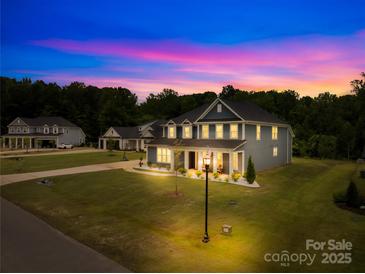 Beautiful two-story home featuring a well-manicured lawn, illuminated by outdoor lighting at dusk at 126 Still Creek Dr, Mooresville, NC 28115