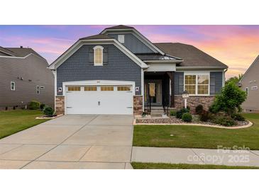 Charming exterior with blue siding, stone accents, manicured lawn, and two car garage at 1663 Tranquility Blvd, Lancaster, SC 29720