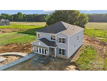 Newly built two-story home featuring gray siding, black roof, and a welcoming covered entryway at 21047 Running Creek Dr # 9, Locust, NC 28097