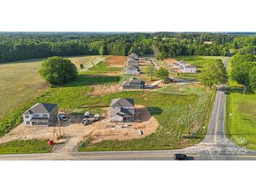 An aerial view shows multiple homes under construction in a new neighborhood surrounded by trees and fields at 21071 Running Creek Dr # 12, Locust, NC 28097