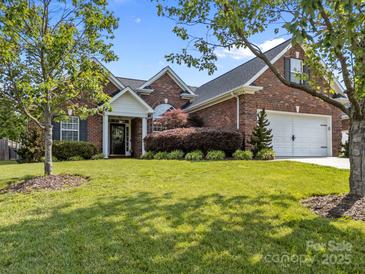 Charming brick home featuring a manicured lawn, attached garage, and inviting front entrance at 3419 Brickyard Ln, Midland, NC 28107