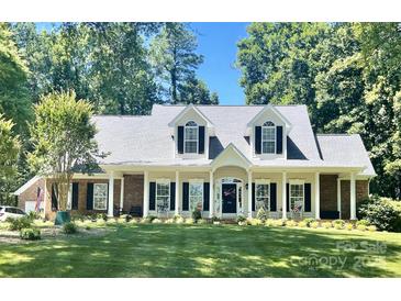 Charming one-story home featuring a manicured lawn, white trim, dormer windows, and welcoming front porch at 390 Robinson Rd, Mooresville, NC 28117
