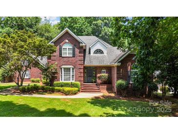 Beautiful brick two-story home with landscaped lawn and manicured shrubs on a sunny day at 150 Pinnacle Shores Dr, Mooresville, NC 28117
