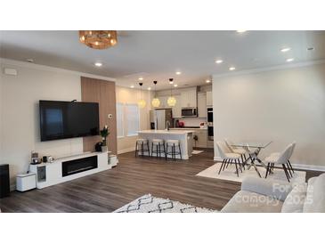 Open-concept living room and kitchen with modern decor, island seating, and stylish light fixtures at 332 Cranford Dr, Pineville, NC 28134