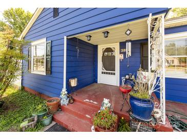 Charming blue home featuring a cozy front porch and decorative landscaping at 455 Wood Ave, Kannapolis, NC 28083