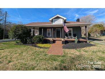 Charming home with a cozy front porch, manicured landscaping, and patriotic American flag display at 101 Sunset Dr, Stanley, NC 28164