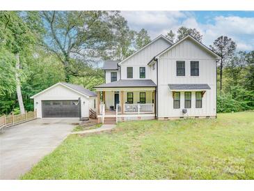 Beautiful two-story farmhouse with white siding, black trim, inviting front porch, and a detached garage at 1062 Willow Ridge Ln, Fort Mill, SC 29707