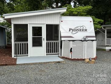 Charming camper with screened porch and white lattice skirting providing a cozy and private outdoor living space at 107 Pine St, New London, NC 28127
