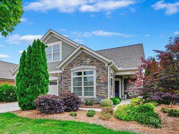 Charming home with stone accents, manicured landscaping, and a well-maintained lawn under a bright blue sky at 1226 Restoration Dr, Waxhaw, NC 28173