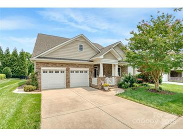 Charming home featuring a stone facade, two-car garage, manicured lawn, and a welcoming front porch at 12910 Meetinghouse Dr, Cornelius, NC 28031