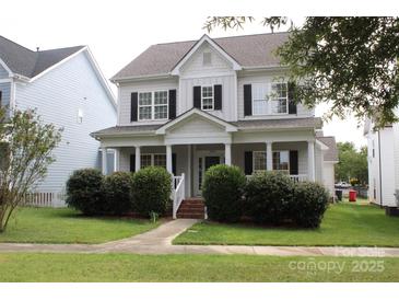Charming two-story home with a welcoming front porch, manicured bushes and black shutters at 19834 Davidson Concord Rd, Davidson, NC 28036