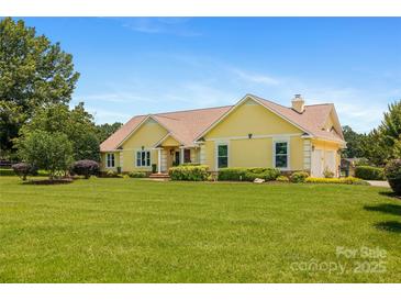 Charming yellow single-story home with a lush green lawn and well-maintained landscaping under a clear blue sky at 205 Harwell Rd, Mooresville, NC 28117