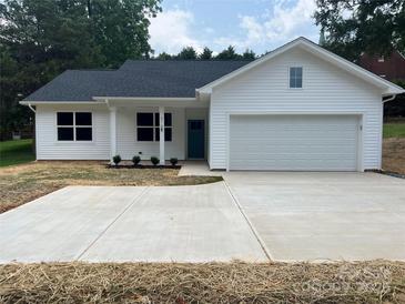 Charming single-story home boasting a white exterior, well-manicured lawn, and an attached garage at 210 Johnson St, Troutman, NC 28116