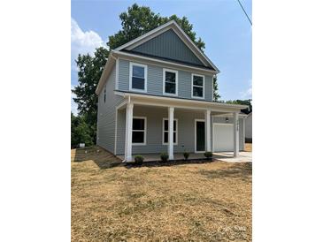 Charming two-story home featuring a welcoming front porch with white columns and an attached one-car garage at 242 North Ave, Troutman, NC 28166