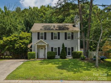 Charming two-story home featuring a well-manicured lawn, a symmetrical facade, and lush surrounding greenery at 3313 Fortis Ln, Matthews, NC 28105