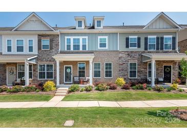 Charming townhome with a well-manicured lawn, inviting front porch and eye-catching architectural details at 5432 Kinsbridge Dr, Charlotte, NC 28227