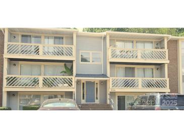Condo exterior with balconies, neutral siding, and a blue front door at 9501-A Shannon Green Dr, Charlotte, NC 28213