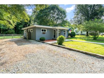 Charming home with gray painted brick and a gravel driveway framed by mature trees in a large yard at 112 Lineberger St, Stanley, NC 28164