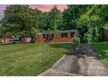 Charming brick home with mature trees, a well-maintained lawn, and a private driveway at 3939 Sheffield Dr, Charlotte, NC 28205