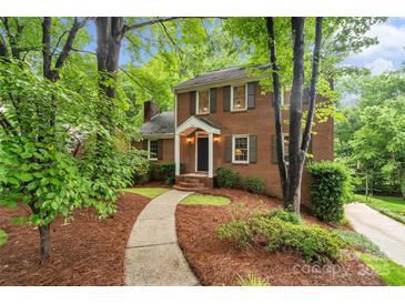 Charming brick home featuring a manicured front yard with mature trees and a walkway to the entrance at 626 Trail Ridge Rd, Matthews, NC 28105
