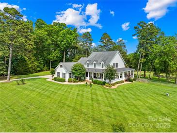 Stunning two-story farmhouse with a wrap-around porch and lush landscaping at 738 Rocky Hollow Trl, Clover, SC 29710