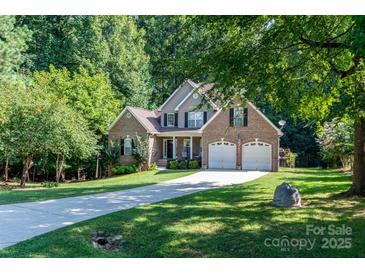 Charming brick home featuring an attached two-car garage, well-manicured lawn, and long driveway at 122 Ardmore Pl, Mooresville, NC 28117