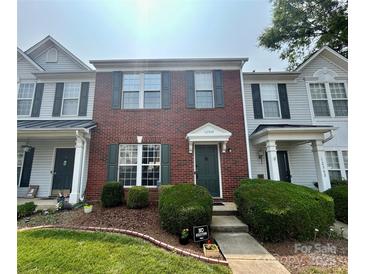 Charming brick townhouse featuring a well-maintained lawn and lush landscaping at 12564 Jessica Pl, Charlotte, NC 28269
