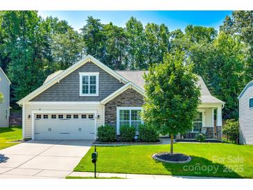 Charming home featuring a manicured lawn, two-car garage, and a mix of stone and gray plank exterior accents at 14727 Brannock Hills Dr, Charlotte, NC 28278