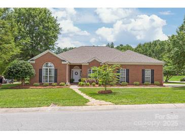 Charming brick home with well-manicured lawn, mature trees, and inviting stone pathway leading to the front door at 502 Roxanne Nw Ct, Concord, NC 28027