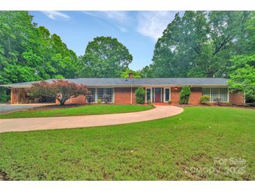 Charming brick home features a well-manicured lawn, mature trees, and a circular driveway, offering classic curb appeal at 514 Wood St, Troy, NC 27371