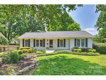 Charming white brick home featuring black shutters, a lush front lawn, and mature trees at 6938 Wrentree Dr, Charlotte, NC 28210