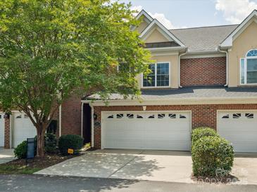 Charming townhome featuring a brick facade, two-car garage, and mature landscaping at 705 Congressional Ln, Fort Mill, SC 29708