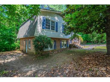 An exterior view of a home with gray and white siding, blue shutters, and surrounded by lush, mature trees at 7320 Ritter Dr, Charlotte, NC 28270