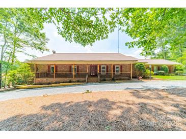 Charming single-story brick home featuring a covered porch and mature trees at 12705 Caldwell Rd, Charlotte, NC 28213