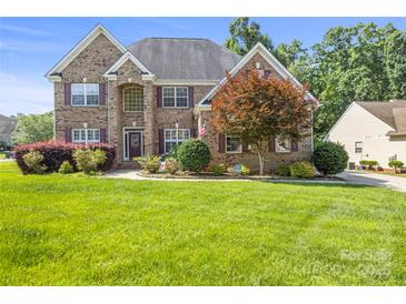 Charming brick home with manicured lawn, colorful landscaping, and lovely curb appeal in a desirable neighborhood at 128 Sugar Thyme Ln, Mooresville, NC 28115