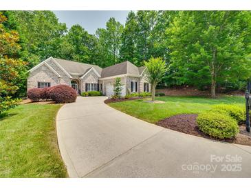 Charming brick home featuring a well-manicured lawn, mature trees, and a long driveway leading to the garage at 16527 Woolwine Rd, Charlotte, NC 28278