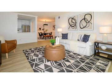 Cozy living room with decorative rug, sofa, and view into the dining area and kitchen at 4754 Hedgemore Dr # E, Charlotte, NC 28209
