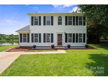 Charming two-story home with classic shutters and manicured lawn overlooking the serene lake at 6516 Laurel Springs Ct, Charlotte, NC 28227