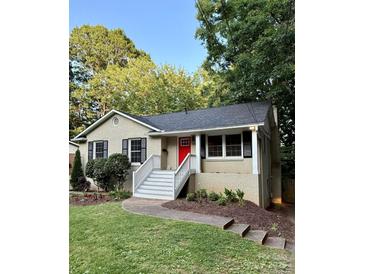 Charming single-story home with a red door, a well-manicured lawn, and front yard landscaping at 6935 Woodstock Dr, Charlotte, NC 28210