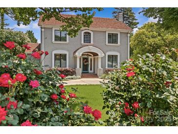 Charming two-story home with gray siding, a red tile roof, and a beautiful landscaped front yard with mature trees and rose bushes at 1619 Providence Rd, Charlotte, NC 28207