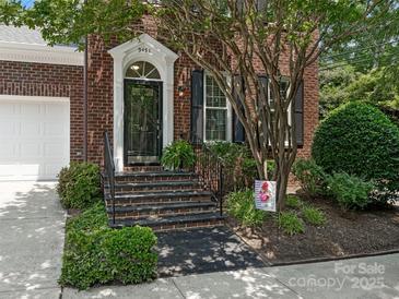 Charming brick home showcasing a stylish front door, black shutters, and lush landscaping at 9451 Bonnie Briar Cir, Charlotte, NC 28277