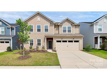 Charming tan two-story home featuring a two-car garage, landscaped yard, and inviting front entrance at 13140 Sudwick Ln, Charlotte, NC 28278