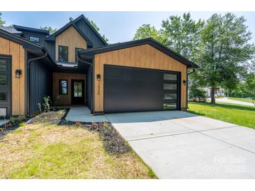 Modern two-story home with black garage door, natural wood accents and manicured lawn at 1520 Enochville Rd, Kannapolis, NC 28081