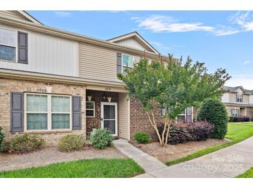 Charming townhome entrance featuring a brick facade, landscaped garden, and well-lit pathway at 6834 Creft Cir, Indian Trail, NC 28079